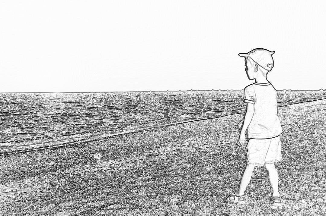 Black and white storyboard line rough sketch, simple pencil drawing of a boy wearing a baseball cap standing on the grassy shore by the sea looking at the horizon with his fishing rod in hand. He has some small bubbles floating around him. The background features an endless ocean with gentle waves in a simple line style with low details and no shading.