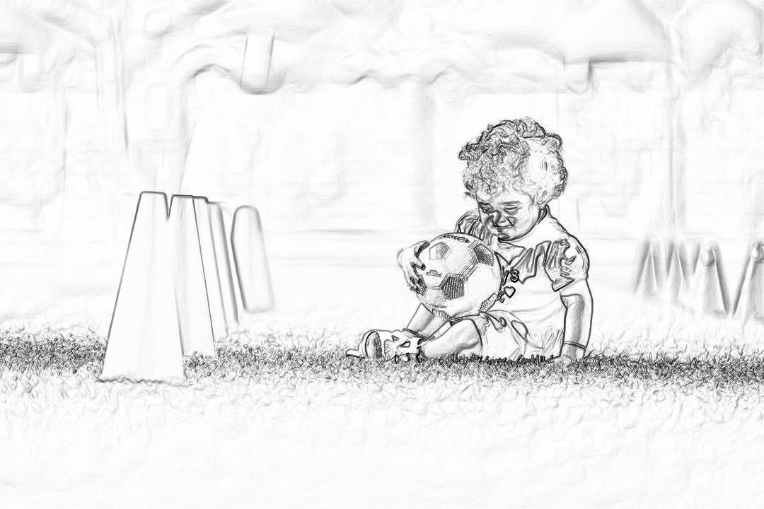 Black and white pencil sketch of an adorable toddler playing with his soccer ball on the grass, surrounded by goal posts. The scene captures her innocent joy as she deeply plays in front of you. Her curly hair is tied back to keep it out of their way. She has a small ponytail that adds character to her appearance. Drawn with soft lines and delicate shading, emphasizing the innocence and charm of childhood sports.