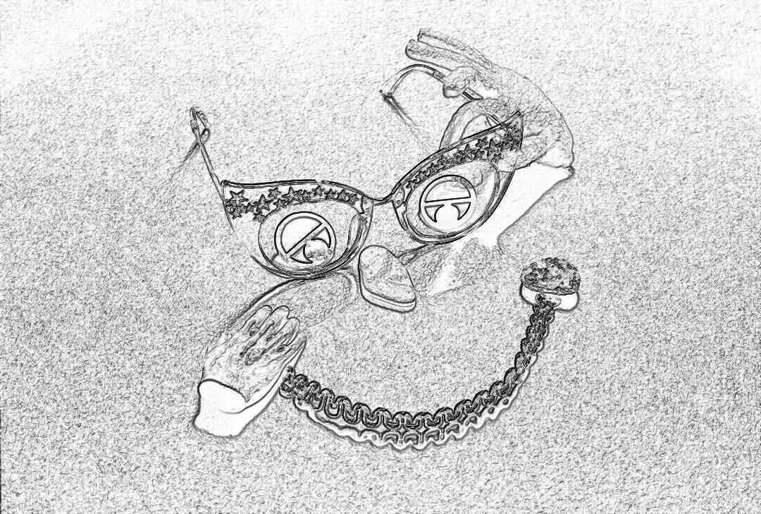 Black and white pencil sketch of an abstract smiley face made from sunglasses, chain necklace with pendants and shoes on the sand.