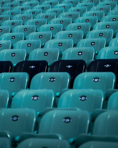 Photograph of seafoam green and black seats in an empty stadium with numbers on the chairs, frontal view, symmetrical composition, f/28, centered, shot in the style of Hasselblad XID, cinematic light --ar 51:64