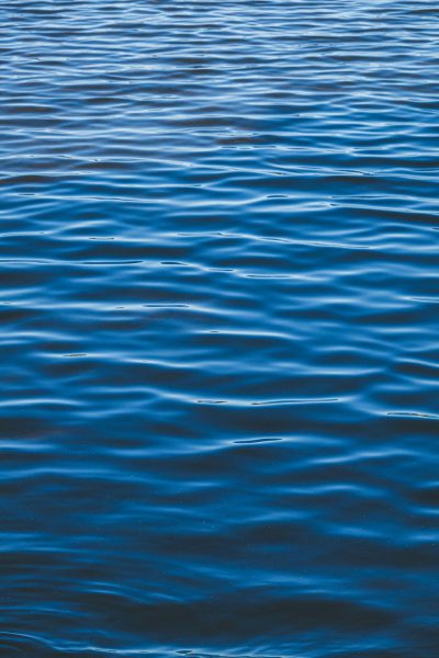 Water surface texture, calm water with ripples, blue color tone, flat view angle, high resolution photography, in the style of Nikon D850 camera with 2470mm f/3.5 lens, natural light. --ar 85:128