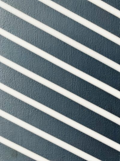 Close up of white diagonal stripes on a navy blue wall, shadowplay, in the style of high resolution photography --ar 3:4