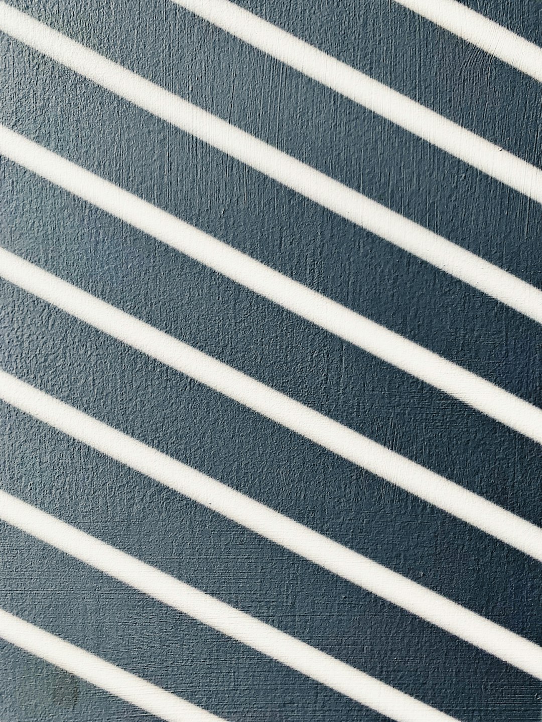 Close up of white diagonal stripes on a navy blue wall, shadowplay, in the style of high resolution photography –ar 3:4