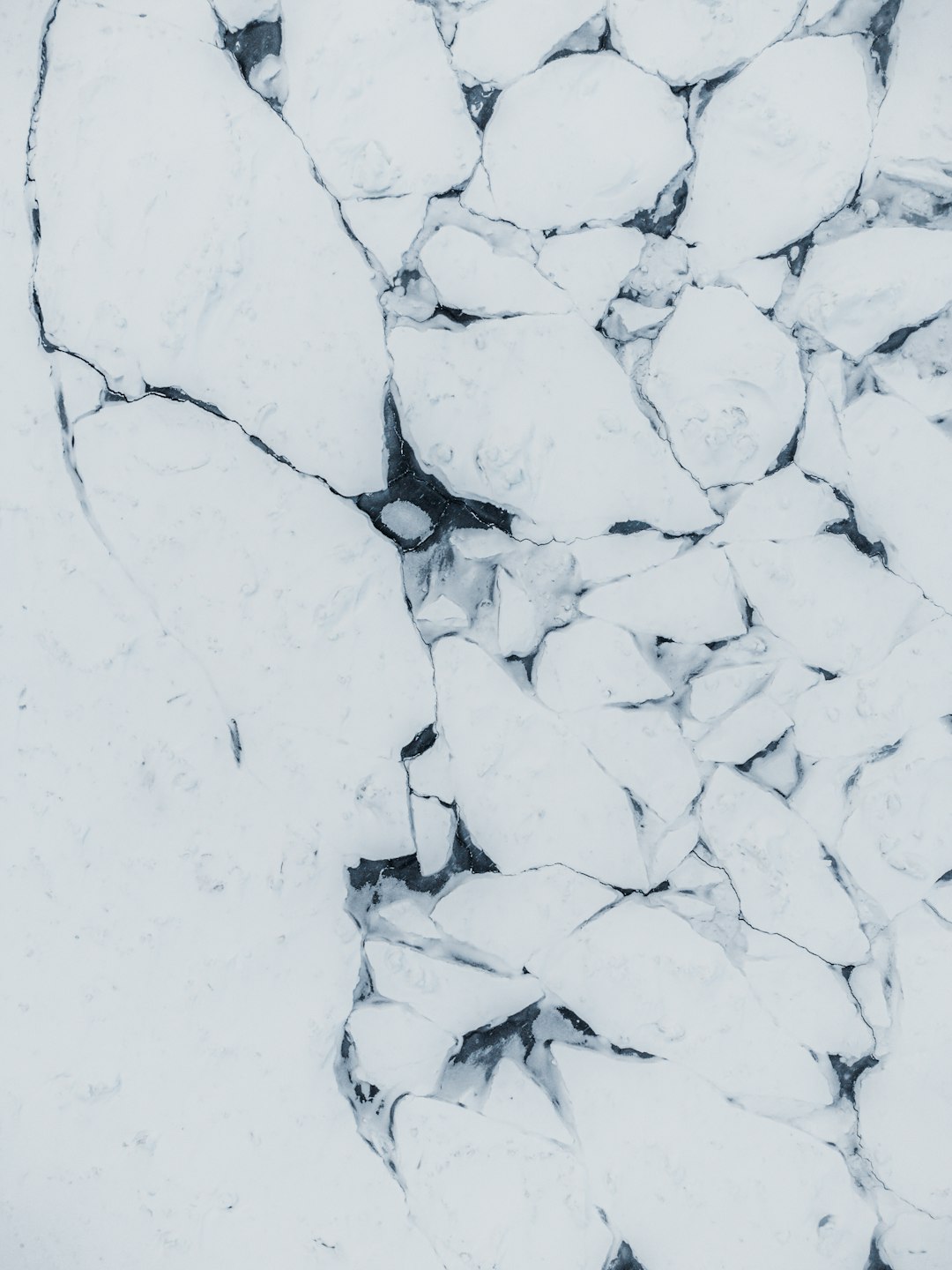 white ice, aerial view from above of cracked white snow and black rocks, topdown shot, drone photography, white background, –ar 3:4