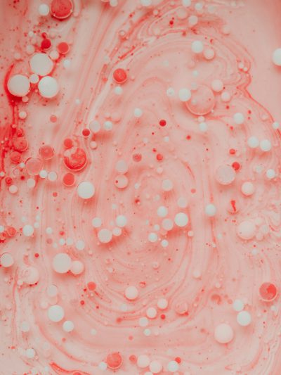 Abstract pink liquid background with white bubbles and red details, top view. Closeup photo. --ar 3:4