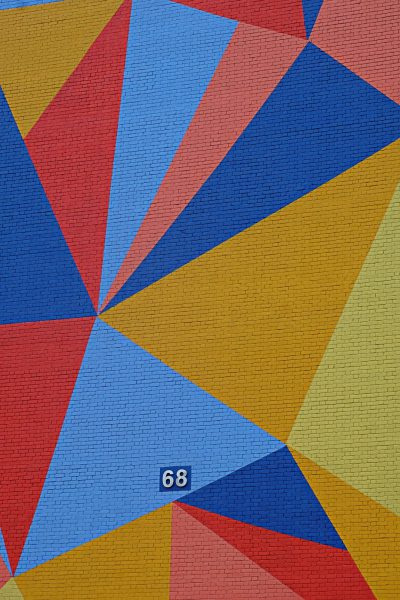 A vibrant geometric pattern of triangles and squares in red, blue, yellow colors on the background wall with number "68" written below it. --ar 85:128