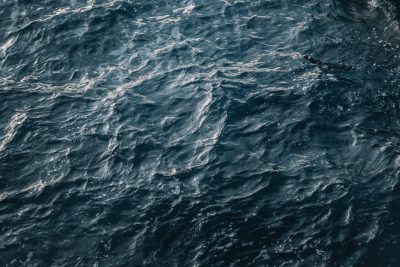 A topdown view of the dark blue sea, capturing its intricate patterns and textures with high detail. The water's surface reflects light, creating ripples that highlight the depth below. Shot in the style of National Geographic photography, using Canon EOS R5 for sharpness and clarity. --ar 128:85