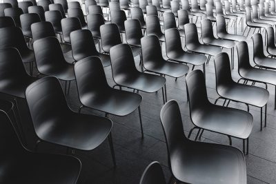 A large group of modern chairs were arranged in rows on the floor in a symmetrical composition. The high resolution photography had a minimalist style with cinematic lighting. A dark grey background was used with a closeup shot that showed the detailed texture. A monochrome color scheme created a balanced and harmonious layout. --ar 128:85