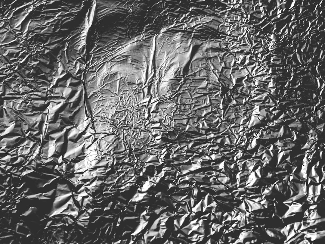 Black crumpled plastic wrap texture background. Shiny foil, monochrome black and white –ar 4:3