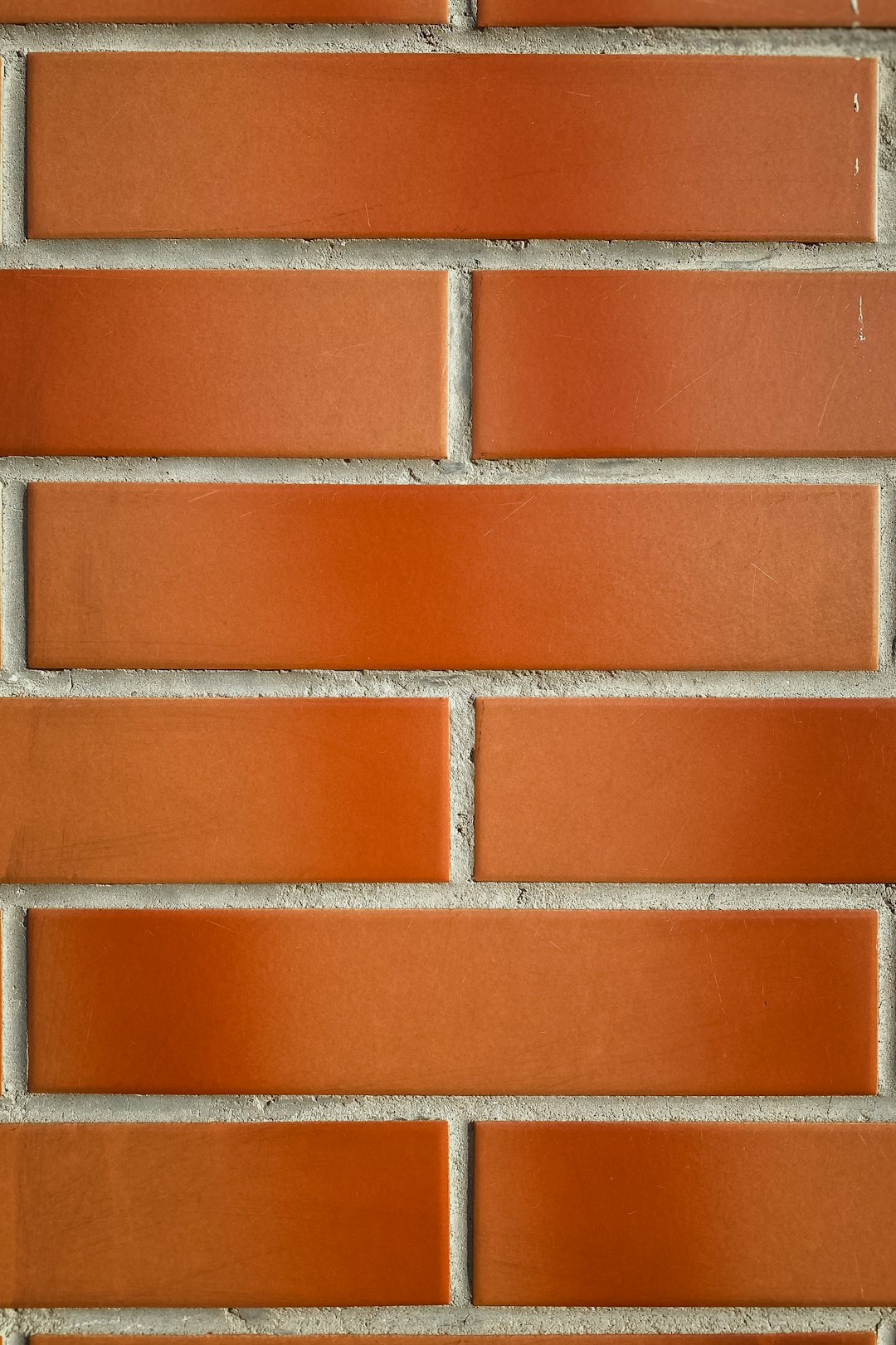 A closeup of an orange brick wall, with each row featuring three horizontal bricks in the same color and shape. The background is plain white to highlight the texture and pattern of the red brick surface. This photograph highlights one of the classic materials used for construction or interior design, with the style resembling a minimalist photograph. –ar 85:128