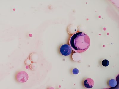 flat lay photography of pink and purple spheres floating in white milk, some bubbles --ar 4:3