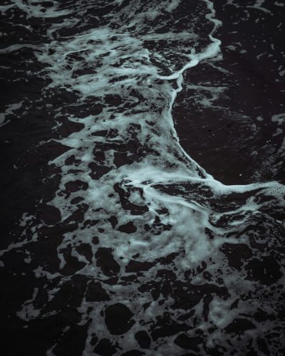 dark ocean water, dark beach, dark night, top view, aerial photography, white waves, dark atmosphere, high contrast, hyper realistic, photography, detailed, texture, --ar 51:64