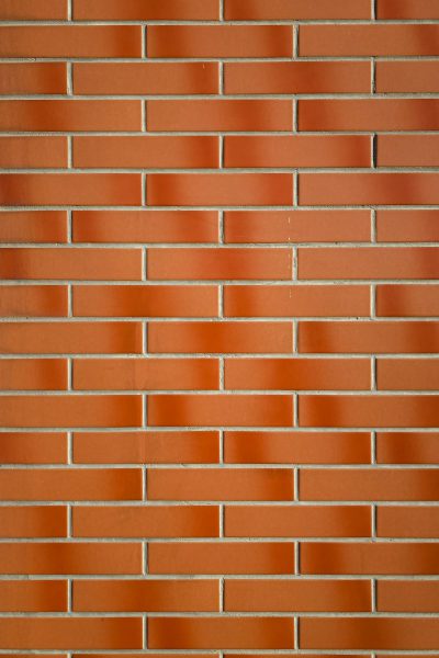 A red brick wall with perfect, uniform bricks arranged in straight lines. The background is solid and flat without any shadows or lighting effects. This design should be minimalist and clean, focusing on the texture of the brick material. Use soft lighting to highlight each individual tile's detail. High resolution. --ar 85:128