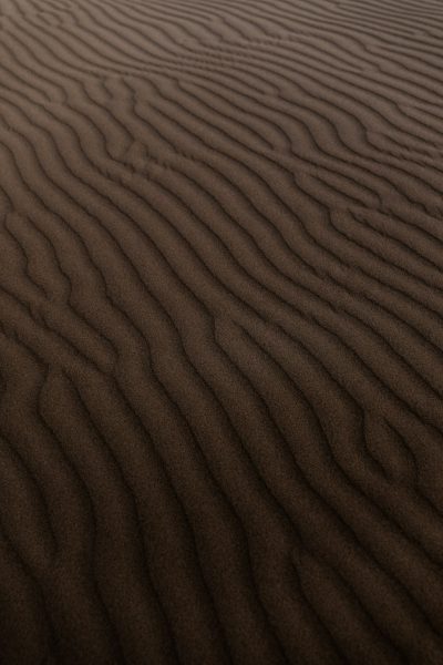 Dark brown sand ripples, closeup, desert background, ultrahigh definition photography, high resolution --ar 85:128