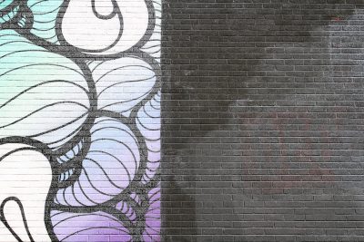 A simple, colorful graffiti design on the left side of an urban brick wall with black grout, featuring white and purple swirls on top of blue patterns, creating a contrast between lightness and shadowy areas. The background is a deep gray color, providing space for creative thinking or visualizing ideas. This art style could be used in street art projects to add depth and texture to city walls, adding a modern touch to traditional murals. --ar 128:85