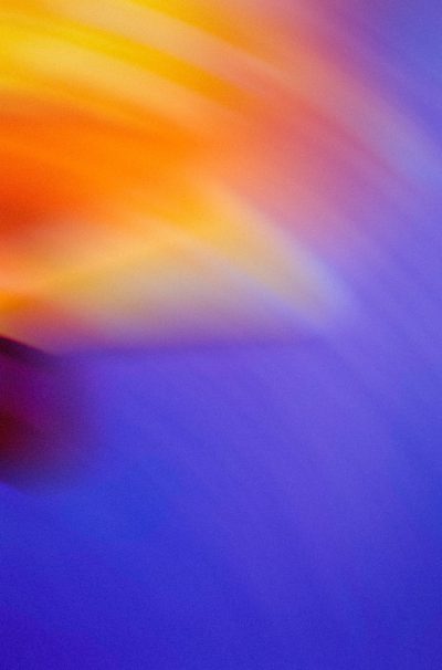 Abstract blur of yellow and orange on a blue background, creating an otherworldly effect. The blurred rays create a dynamic contrast with the deep blues, evoking feelings of mystery and depth. This composition is ideal for conveying a sense of calmness or surrealism in design projects. The photograph was taken with a Canon EOS A7 camera using a macro lens at an f/2.8 aperture setting, in the style of surrealist photography. --ar 21:32