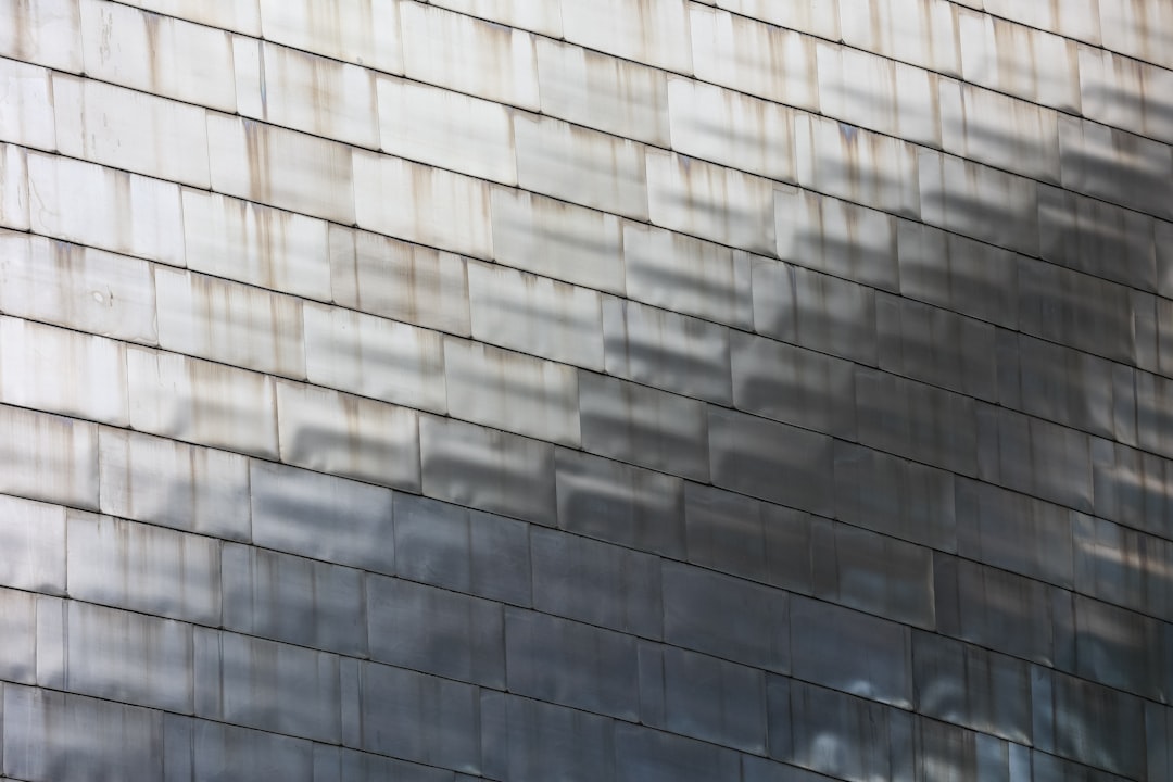 Photograph of the facade wall cladding made from gray metal shingles, with shadows and reflections in the style of the facade. –ar 128:85