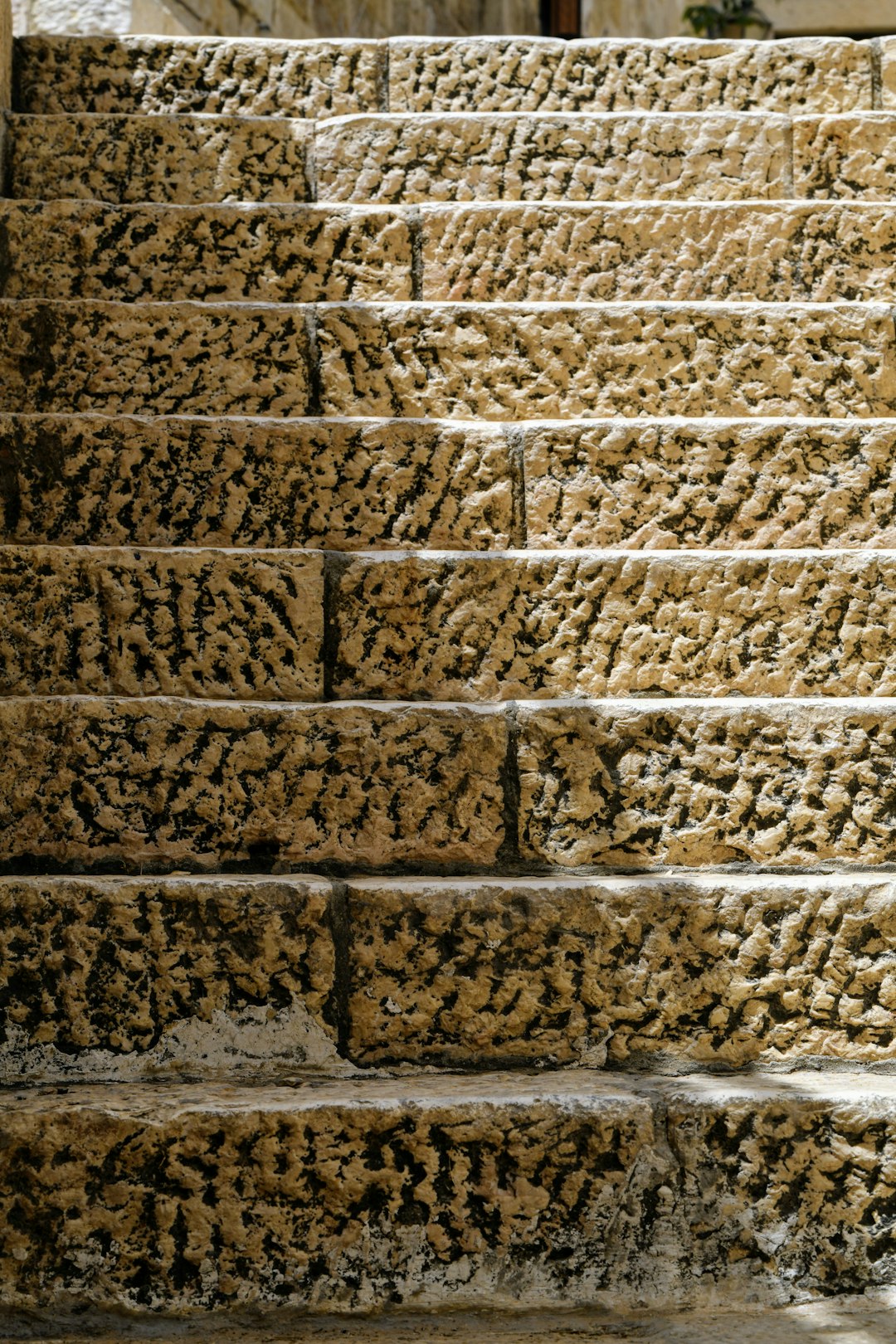 An old stone staircase with rough textures, aged stones and weathered surfaces in a closeup shot with warm tones and detailed textures, with an ancient city of Jerusalem background, photography. –ar 85:128