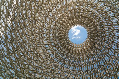 The hexagonal structure of the stacked bamboo frame forms an opening in its center, through which one can see blue sky and white clouds outside. The entire building is covered with bamboo sticks arranged in spiral patterns to create the effect of a giant honeycomb, giving people a sense that they have entered another world of nature. In closeup photography, the details of each wooden stick are clearly visible. --ar 128:85