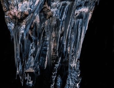 an extreme close up photograph of the rock formations inside an underground cave, hanging icicles and black shadows, lit by moonlight, taken with Sony Alpha A7 III camera --ar 64:49