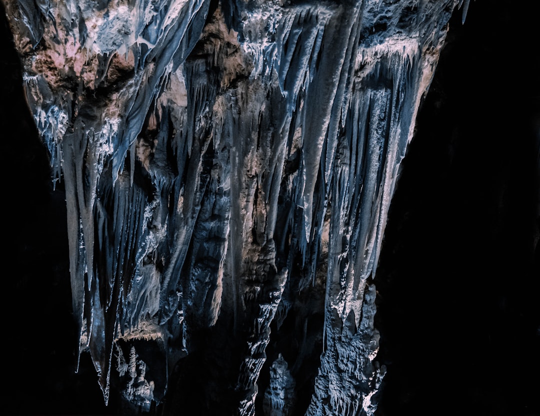 an extreme close up photograph of the rock formations inside an underground cave, hanging icicles and black shadows, lit by moonlight, taken with Sony Alpha A7 III camera –ar 64:49