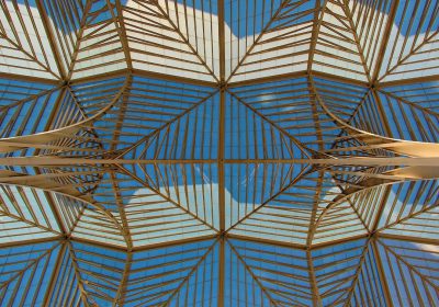 An architectural photograph of the roof structure of Las Stringas in the Tent, Lisbon. The skylight is made out of wood and glass. It has symmetrical geometric patterns that mirror each other. Use a Sony Alpha A7 III camera with an FE 24-85mm f/3.5 to 60 mm lens at F/9 aperture setting. Capture the architecture from below. Vibrant colors. High resolution. --ar 128:89