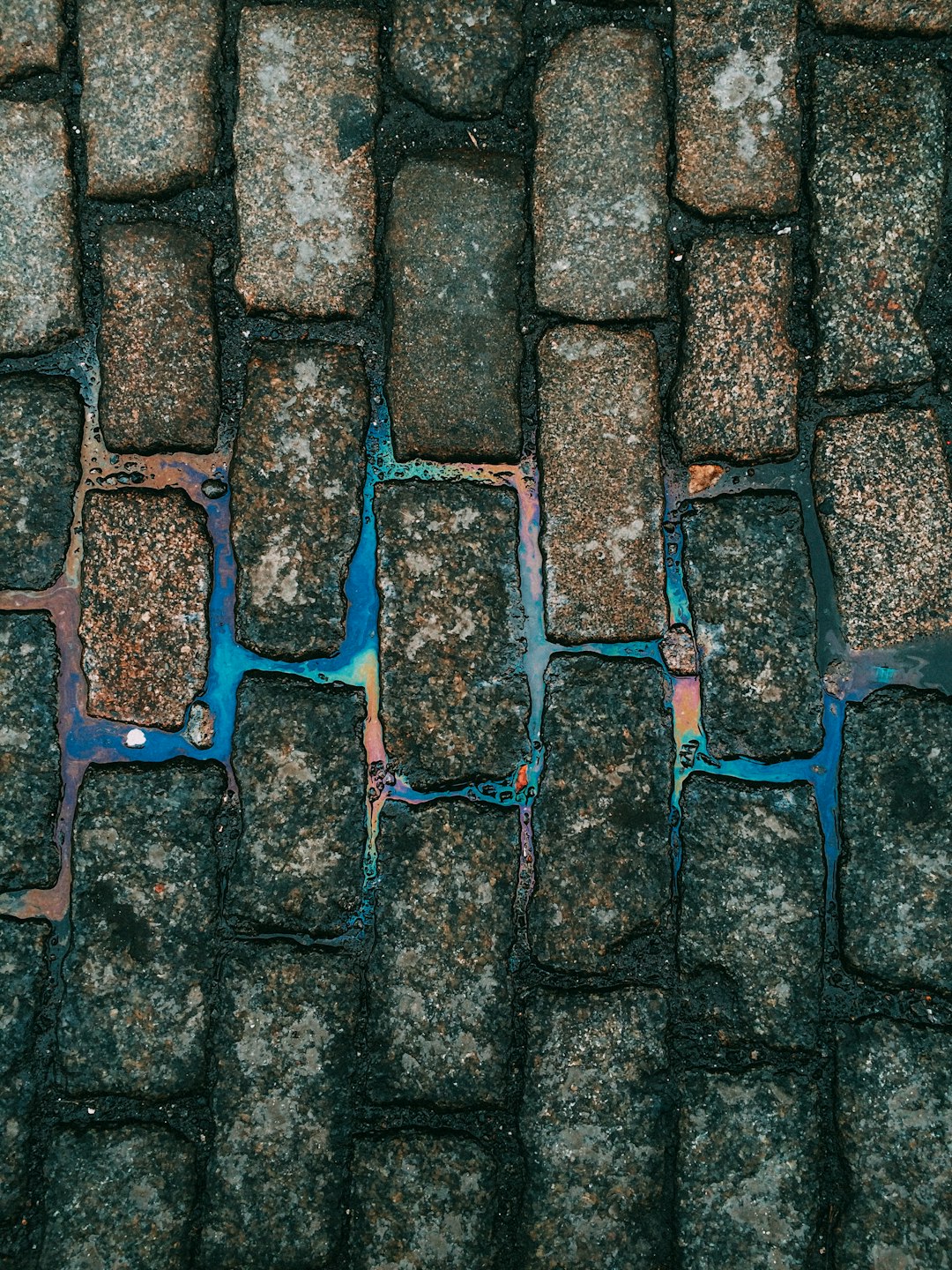 A photograph of a cobblestone street with blue and green oil stains, taken from a top view, with high resolution photography, insanely detailed fine details, isolated on a white background, a stock photo with professional color grading and an award winning composition, lit with cinematic lighting on an overcast day, photographed with a 35 mm lens at f20, in the style of a Canon EOS R6s Mark II. –ar 3:4