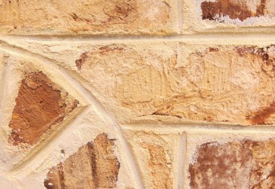 Closeup of an old, weathered beige stone wall with intricate details and textures. The texture is very detailed, showing the different shapes and sizes of bricks, as well as signs of wear and tear such as chipped edges or rust spots. This closeup shot captures the beauty in imperfection and history that each brick holds within its surface. The background should be plain to highlight the detail on the wall itself. --ar 16:11