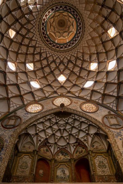 A photo of the ceiling and walls inside Gole parallel from below in an old mesh architectural style showing Persian ceramic tiles, Islamic geometric patterns on them, a dome shape with some skylight windows and decorative glass screens on top, shot in the style of Canon EOS R6 Mark II Mirrorless, natural lighting, ultra realistic, cinematic photography. --ar 85:128