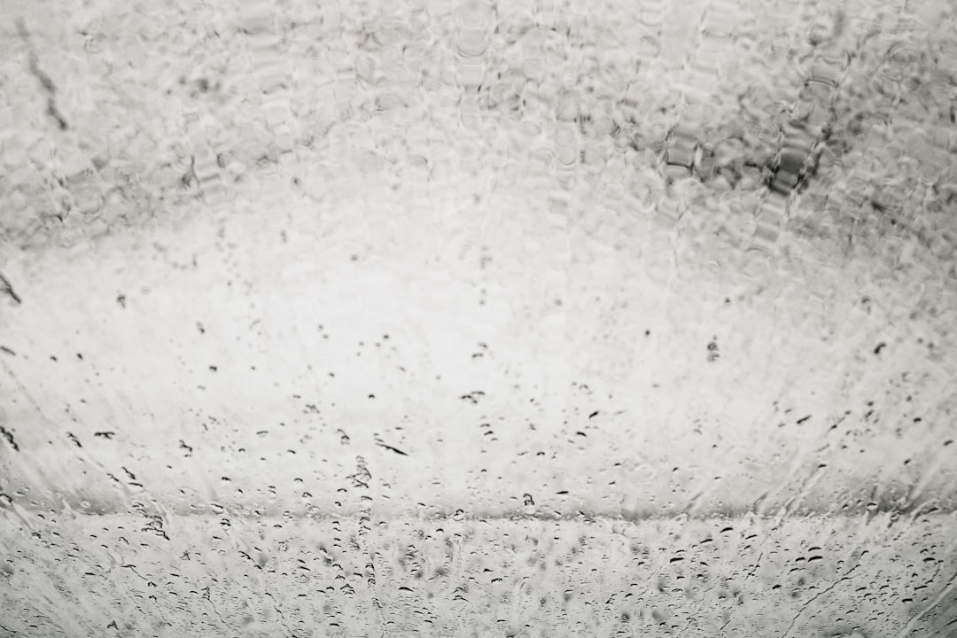 photograph of the interior wall of an old white car wash, water droplets on glass, monochrome –ar 128:85