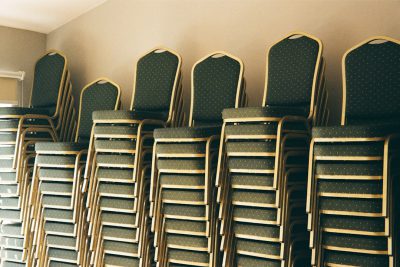 photograph of Stacks of chairs in the room for an corporate event, shot on Fujifilm Pro 400H --ar 128:85