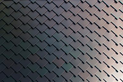 Abstract background of dark gray color with an ornament in the form of chevronshaped squares, with copy space. A shiny metal surface of tiles on roof or wall. Modern minimalist design with geometric shapes. Wide format. High resolution --ar 128:85