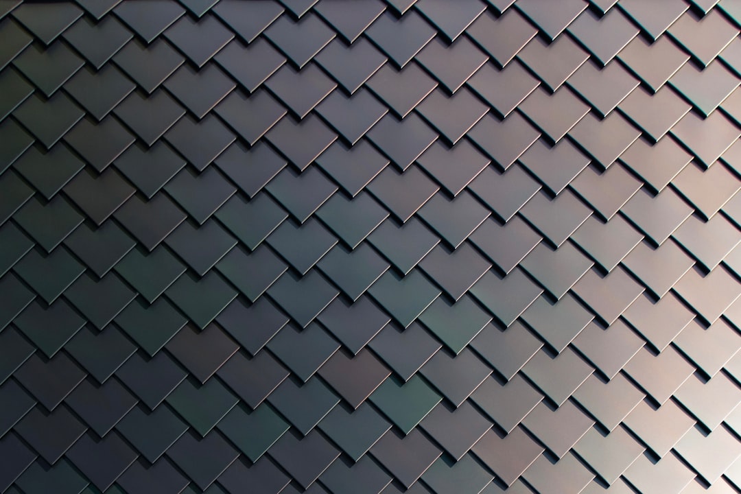 Abstract background of dark gray color with an ornament in the form of chevronshaped squares, with copy space. A shiny metal surface of tiles on roof or wall. Modern minimalist design with geometric shapes. Wide format. High resolution –ar 128:85