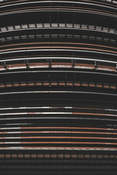 A photo of the exterior wall texture of an ovalshaped stadium, featuring horizontal stripes in shades of black and brown. The image captures the unique architecture with its curved lines and patterned details. This topdown view highlights how these strips come together to form the overall structure of the building. Shot by Nikon D850 with high resolution, cinematic lighting --ar 85:128