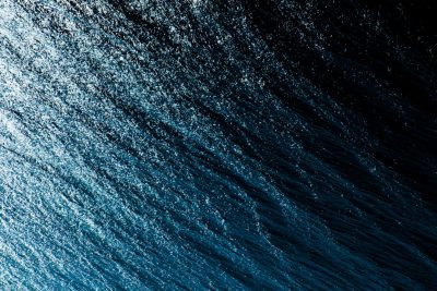 A closeup of the dark blue sea, with gentle ripples and light reflections on its surface. The camera captures an overhead view of the entire scene from above. The composition emphasizes the beauty of the water's texture against a black background. High resolution photography captures the photo realistically. Shot in the style of Hasselblad H6D400c Mf XCD lens. --ar 128:85