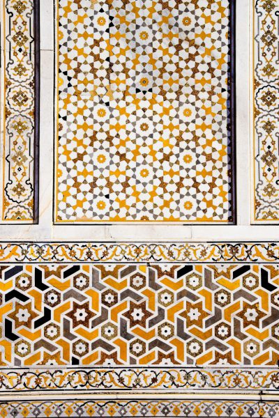 A closeup of the intricate geometric patterns on an Islamic mosaic, showcasing yellow and white hues against a marble stone background. The symmetrical design features traditional Indian motifs such as stars or hearts, adding depth to its appearance. This composition highlights both artistic craftsmanship and cultural significance in Arabic art, in the style of traditional Islamic patterns. --ar 85:128