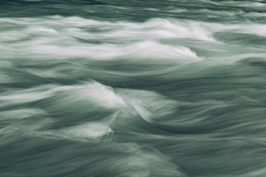 Abstract view of the rapids on Napoleon’s river, featuring dynamic water patterns and soft green hues. The camera focuses in closeup to capture details like ripples or splashes against a blurred background. This composition emphasizes the energy and movement associated with powerful water, suitable for creative use in various applications. The style emphasizes closeup details of water movement against a blurred background, capturing the energy of rapids in soft green hues. –ar 128:85