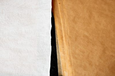 Close up of white and brown parchment paper next to each other, black background, macro photography --ar 128:85