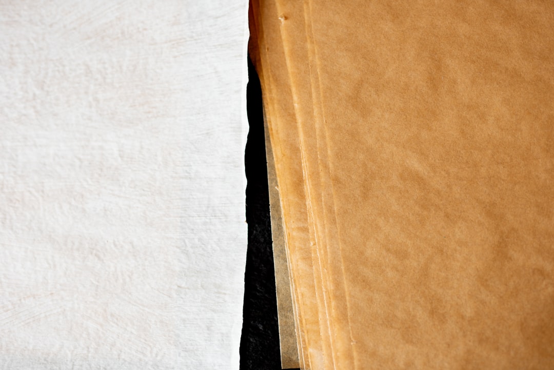 Close up of white and brown parchment paper next to each other, black background, macro photography –ar 128:85