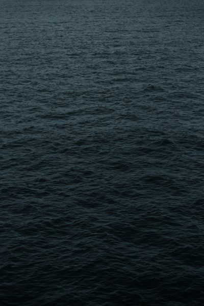 Dark blue water with a flat, dark gray background and no waves on the surface of the sea in a minimalist style with a simple background. A high resolution, hyperrealistic aerial shot in the style of reallife photography with detail from a top view as a professional photograph. --ar 85:128