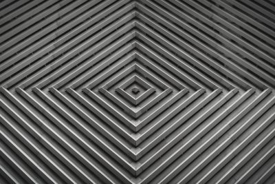 A black and white geometric pattern with lines that form squares, triangles or spirals. The background is made of gray metal and has a symmetrical design in the style of modern art. --ar 128:85