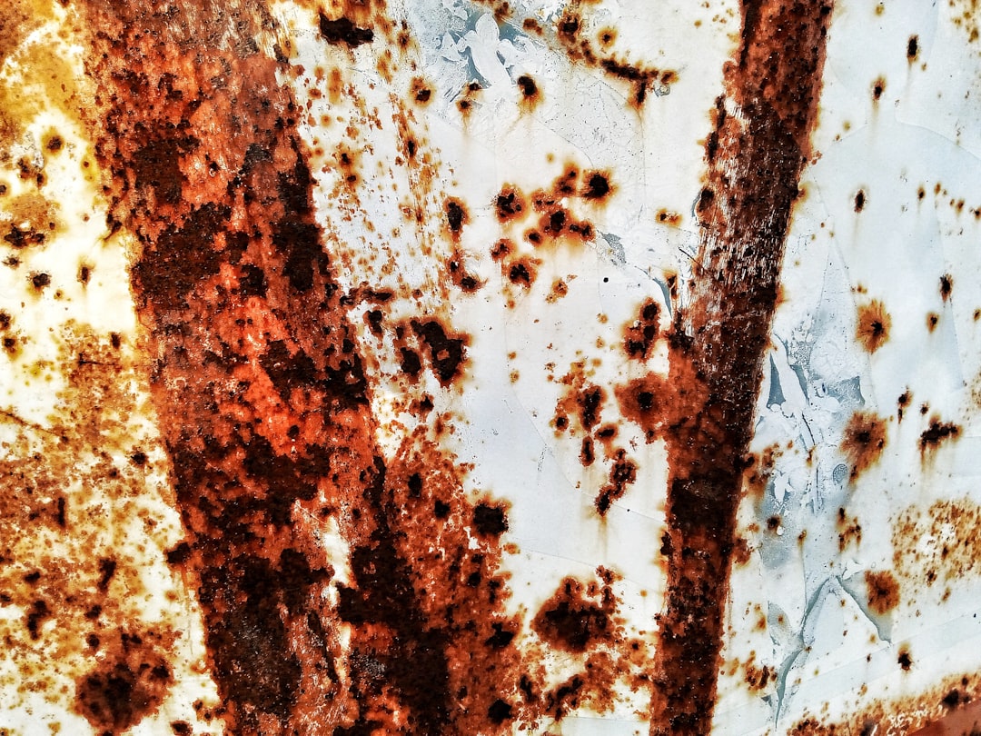 A closeup of rust on white metal, with visible details and textures. The background is plain white to highlight the rusty texture. High resolution, realistic photo, with professional photography and full focus. The photo is in the style of full focus. –ar 4:3
