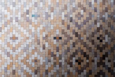 A wall made of square tiles in different shades of brown, grey and silver. The tile pattern is seamless and uniform throughout the whole background. --ar 128:85