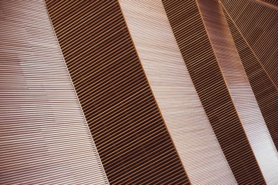 A close up of an architectural building made from copper vertical slats, the lines and angles create beautiful light refractions on the surface of each one, creating a stunning effect. --ar 128:85