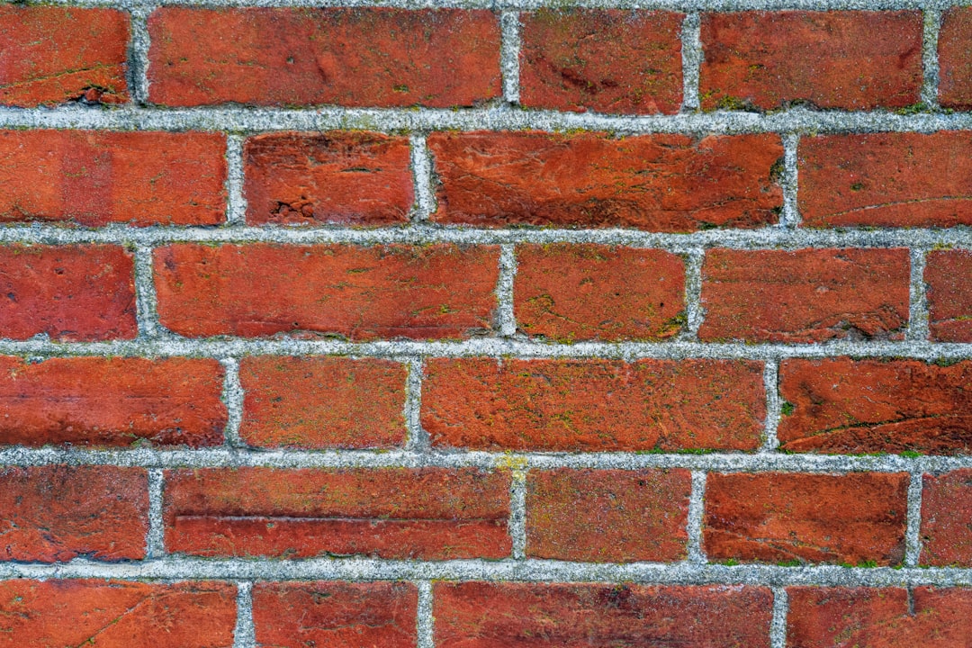 Closeup of a red brick wall texture with gray grout lines in the background. –ar 128:85