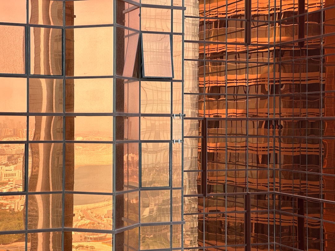 The peach and brown glass facade of a skyscraper, a Dubai cityscape view from a window, a building under construction, an industrial mesh structure, a warm sunset light. –ar 4:3