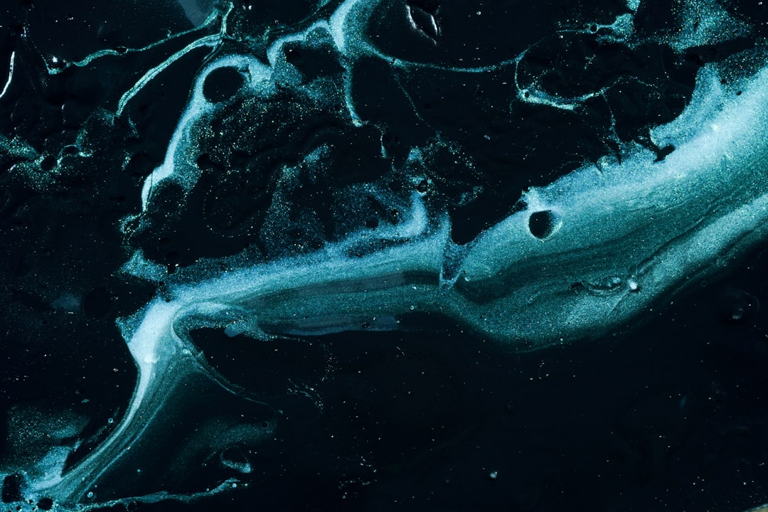 A dark blue and black background with swirling patterns of white paint, resembling the surface of an ocean at night. The color contrast is striking against the deep darkness around it, creating a sense of depth in space. A small amount of light reflections can be seen on some parts of the fluid shapes, adding to its celestial appearance. This image would make for a visually stunning abstract design that captures attention., ultrarealistic photograph captured, highresolution 3D render using Canon EOS5d Mark III camera with lens t0 visible –ar 128:85