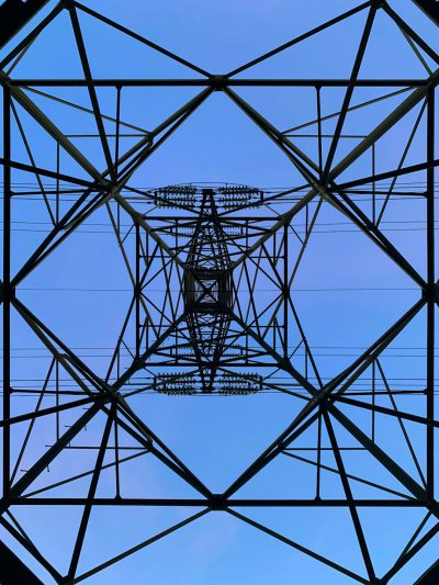 a symmetrical geometric pattern of an electric pammu tower, blue sky background, straight on camera view from the ground looking up at it, hyper realistic photography --ar 3:4