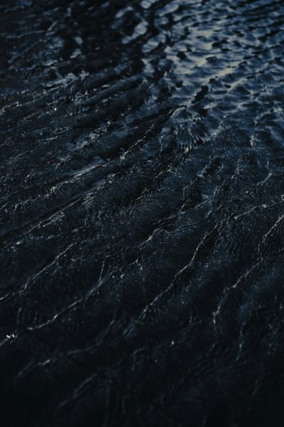 Dark waters, ripples on the surface, top view, high resolution photography, hyper realistic in the style of cinematic light, high contrast --ar 85:128