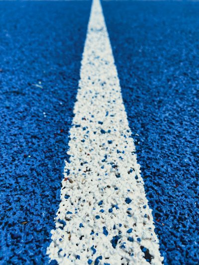 A closeup of the white line on blue asphalt, symbolizing precision and focus in sports events. The background is clear with no other elements to draw attention away from it. The overall composition emphasizes the simplicity yet importance of that single line. Photography in the style of Canon EOS R5 camera.